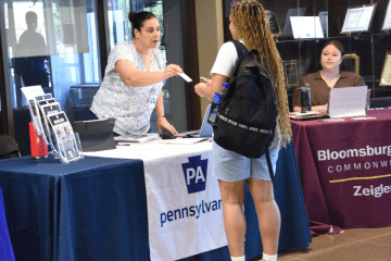 Julie Tressler hands a student her business card at one of the Career Expos on the 粉红女郎sburg campus