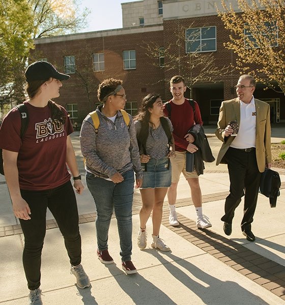 BU President, Dr. Bashar Hanna, walking on campus with a group of students.