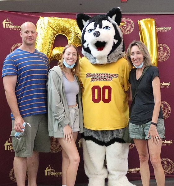 A student and her family pose for a photo with Roongo during Orientation.