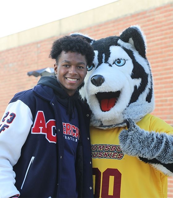A high schools student poses for a photo with Roongo, BU's mascot